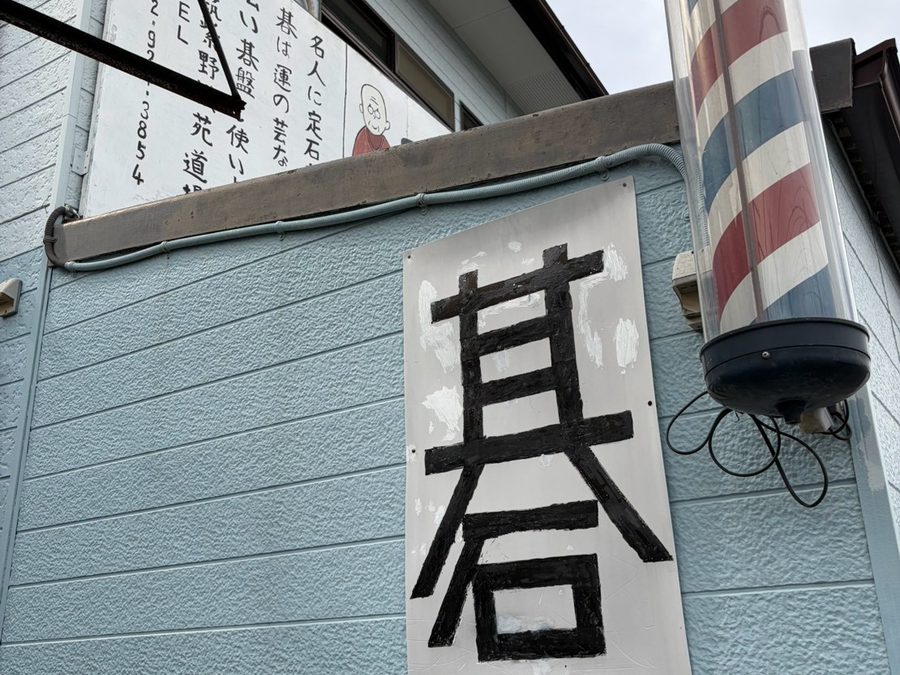 建物側面の壁に掲げた「碁」の看板